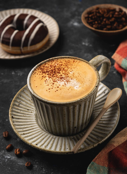 coffee in a cup with a donut and coffee grains, dark background - Photo, Image