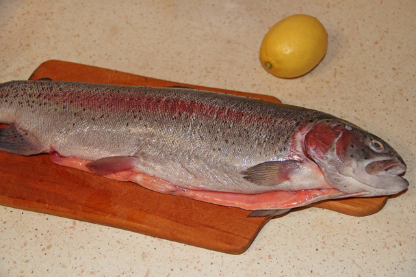 Ψάρια πέστροφα σε έτοιμο για μαγείρεμα με λεμόνι. Πιάτο νόστιμο ψάρι - Φωτογραφία, εικόνα