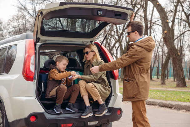 giovane famiglia imballaggio per i viaggi in auto. mettere borse nel bagagliaio
 - Foto, immagini