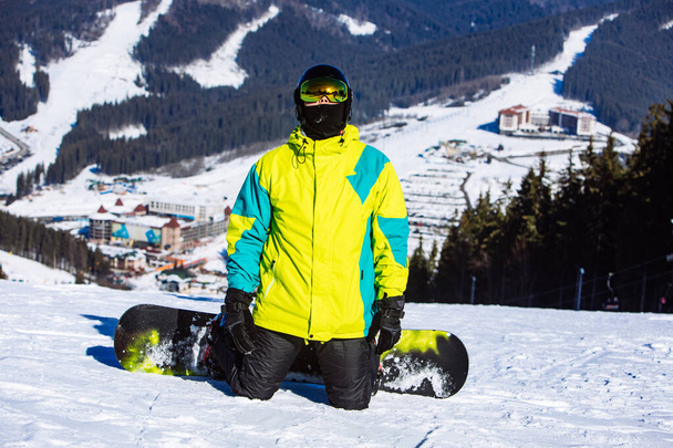man op de top van de heuvel met snowboard in zonnige dag - Foto, afbeelding