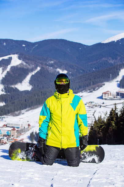 muž na vrcholu kopce se snowboardem ve slunečný den - Fotografie, Obrázek