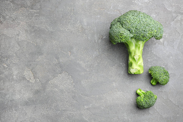 Flat lay composition of fresh green broccoli on grey stone table, space for text - Foto, imagen