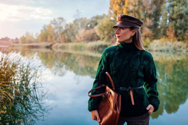 Φθινοπωρινή μόδα Νεαρή γυναίκα φοράει κομψά ρούχα και κρατά τσάντα σε εξωτερικούς χώρους. Ενδύματα και αξεσουάρ - Φωτογραφία, εικόνα