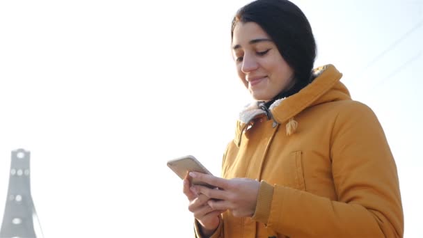 Krásná brunetka drží v rukou chytrý telefon. Zpomalený pohyb - Záběry, video