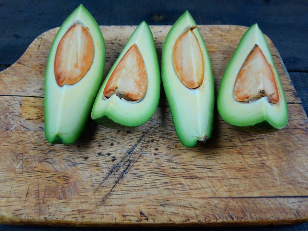 Four beautiful and tasty slices of avocado lie on a cutting board - Photo, Image