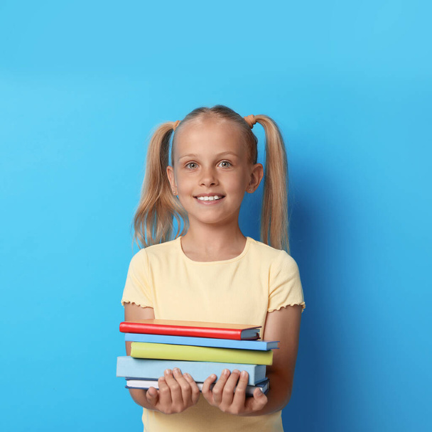 Portrait of cute little girl with books on blue background. Reading concept - Foto, immagini
