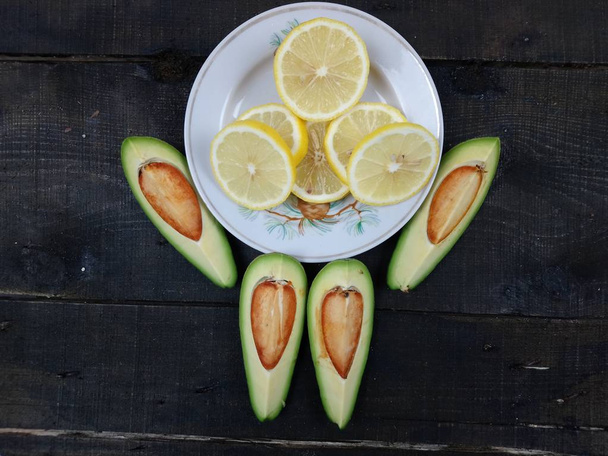 Un plato con limones en rodajas y cuatro rebanadas de aguacate yacen sobre la mesa
  - Foto, Imagen