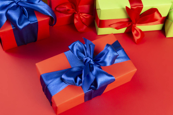 Red gift box with a blue ribbon on a red background. Lots of Christmas gift boxes - Foto, immagini