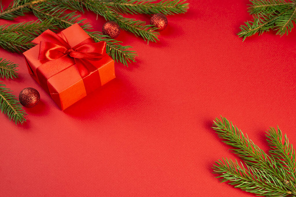 クリスマスの構図。赤いギフト、トウヒの枝、赤い背景の赤い装飾。クリスマス、冬、新年のコンセプト。フラットレイアウト、トップビュー、コピースペース - 写真・画像