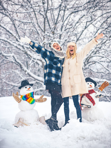 Students party and Christmas celebration. Happy girl playing with a snowman on a snowy winter walk. Christmas Girl and snowman on white snow background. - Fotografie, Obrázek