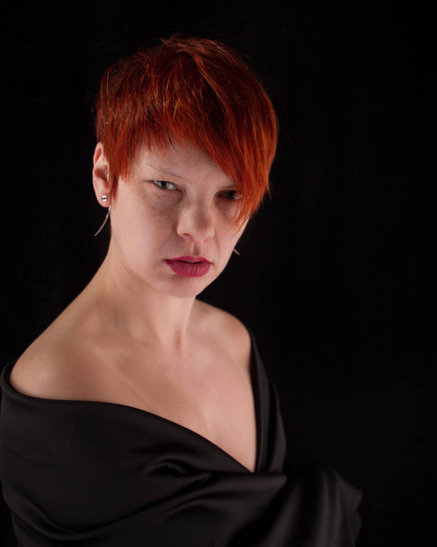 Portrait d'une femme rousse d'âge moyen aux épaules nues sur fond noir, mise au point sélective
 - Photo, image