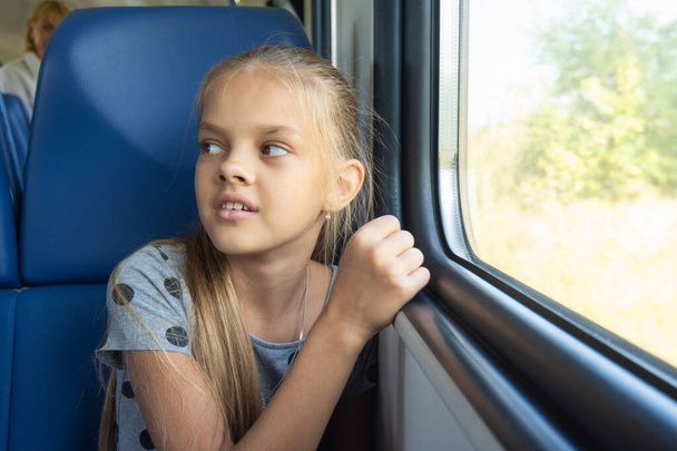 Meisje zittend bij het raam in een elektrische treinwagon - Foto, afbeelding