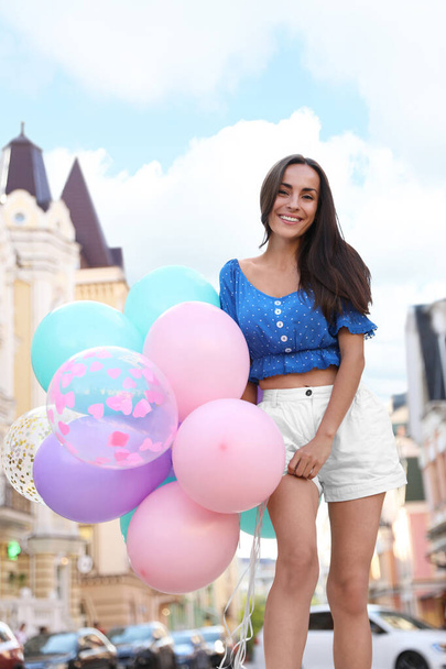 Beautiful young woman with color balloons on city street - Foto, Bild