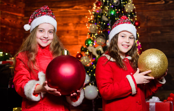 Udekoruj choinkę razem. Dziewczyny siostry Mikołajowe kostiumy. Dzieci urocze przyjaciele spełniają święta Bożego Narodzenia. Rodzina świętuje święta. Koncepcja braterstwa. Świąteczna atmosfera Boże Narodzenie - Zdjęcie, obraz