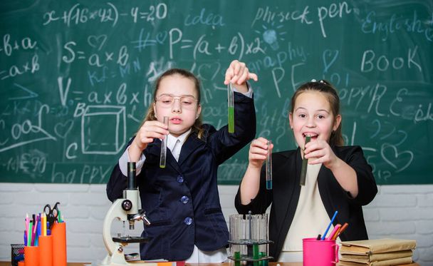 Basic knowledge of chemistry. Girls study chemistry. Make studying chemistry interesting. Microscope and test tubes on table. Educational experiment concept. Be careful performing chemical reaction - Foto, Imagem