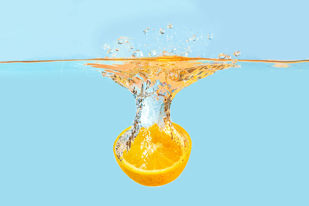Chute de la moitié orange dans l'eau sur fond clair
 - Photo, image