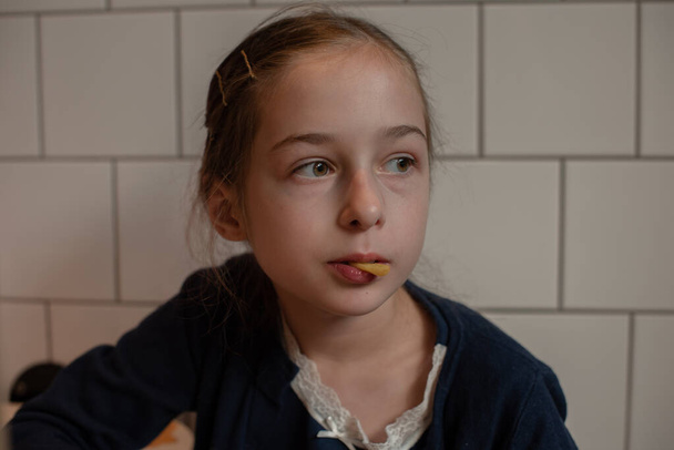 Boldog tini lány hamburgert és sült krumplit eszik. Iskoláslány eszik egy burgerand sült krumplit - Fotó, kép
