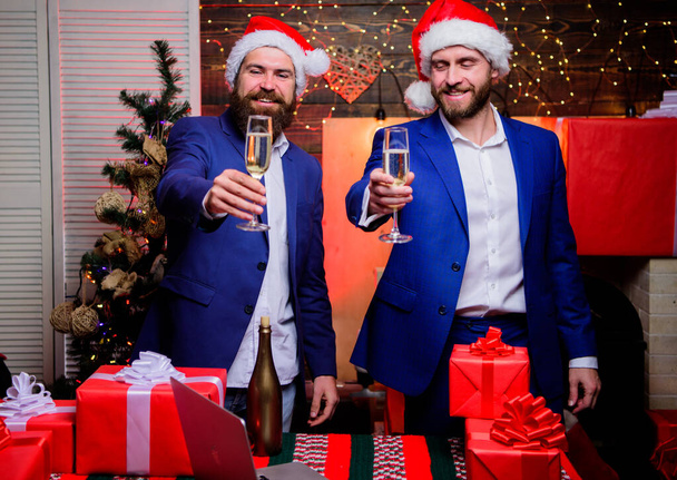 Party with champagne. Business people drink champagne at party. Colleagues celebrate new year. Men formal suits and santa hats hold champagne glasses. Cheers concept. New year corporate party - Photo, Image