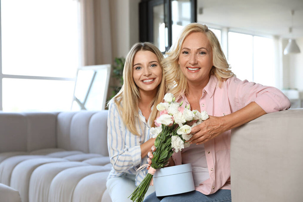 Young woman congratulating her mother in living room - Fotó, kép