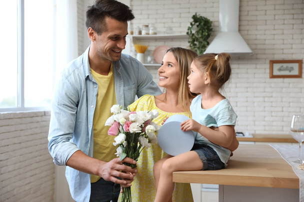 Happy man congratulating his little daughter and wife in kitchen - Photo, Image
