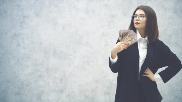 Resmi takım elbiseli sevimli genç bir iş kadını, eli akimbo, yüzüne yakın para banknotları fanı sallıyor, rüzgar yapıyor. Hava çok sıcak.. - Video, Çekim