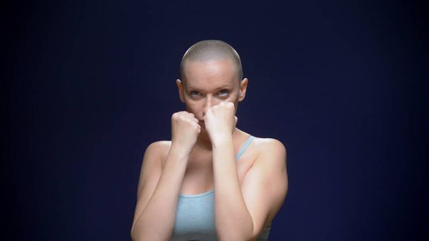 bald woman boxing to the camera against a dark background - Photo, Image