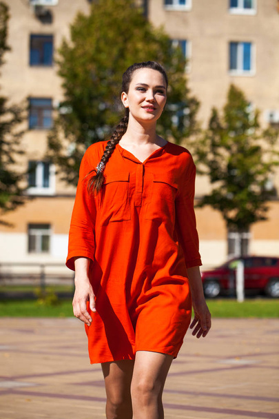 Young beautiful woman in red dress walking in summer street - Fotoğraf, Görsel
