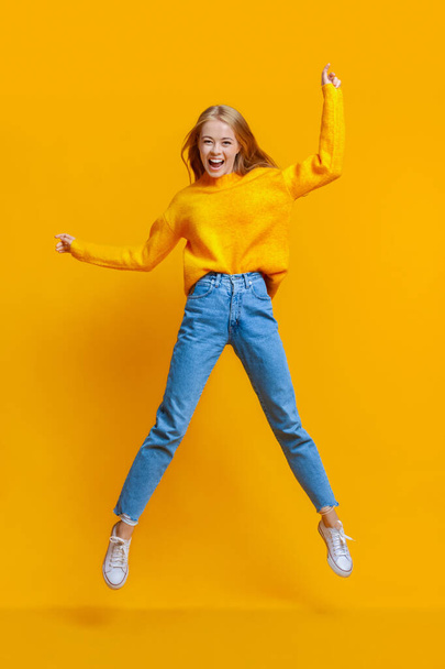 Euphoric teen girl jumping in air with hands up - Fotoğraf, Görsel