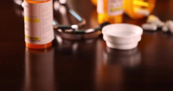 A nem szabadalmaztatott gyógyszeres palackok, tabletták és sztetoszkópok lassú burkolása a sötét fa felületen. - Felvétel, videó