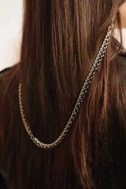 Heavy chain at the points of metal on the dark hair of a young girl. Metal stylish eyeglass chain - Zdjęcie, obraz