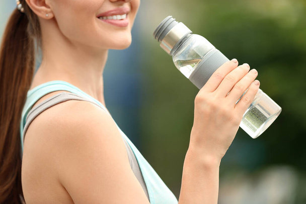 Young woman with bottle of water outdoors, closeup. Refreshing drink - Foto, afbeelding