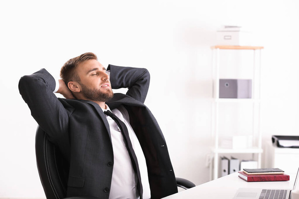 Красивый бизнесмен расслабляется в офисе
 - Фото, изображение