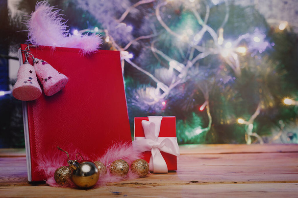 Duża książka życzeń świątecznych z zabawkami choinkowymi i dekoracjami na drewnianym stole. Czytany skórzany notatnik - prezent na Boże Narodzenie lub Nowy Rok - Zdjęcie, obraz