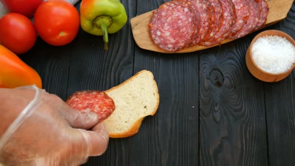 Homemade kitchen. Human hands preparing sandwich of chopped salami and tomato. Concept of making fast food. - Footage, Video