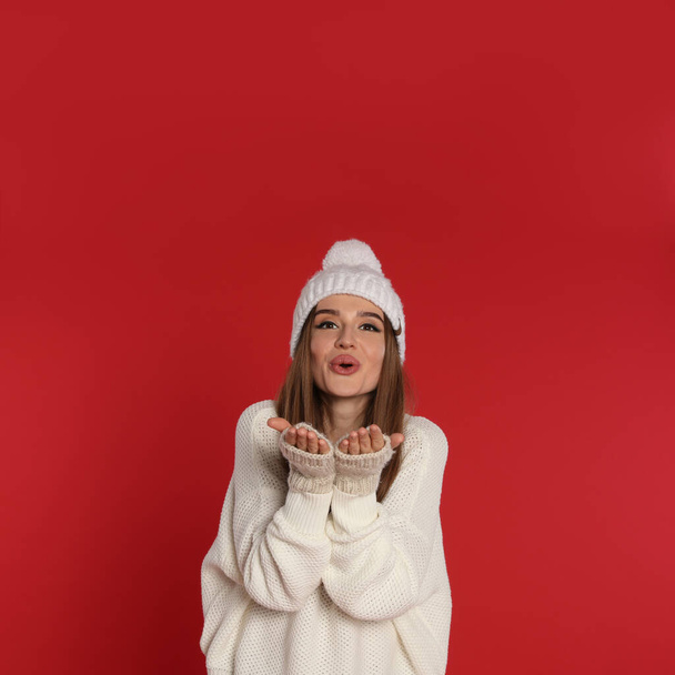 Beautiful young woman in white sweater and hat on red background. Winter season - Fotografie, Obrázek