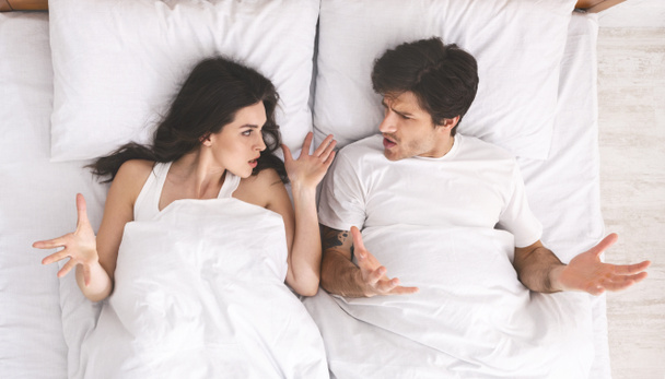 Nuori vihainen pari huutaa toisilleen sängyssä
 - Valokuva, kuva