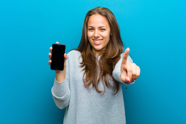 young woman with a mobile phone against blue background - Foto, afbeelding