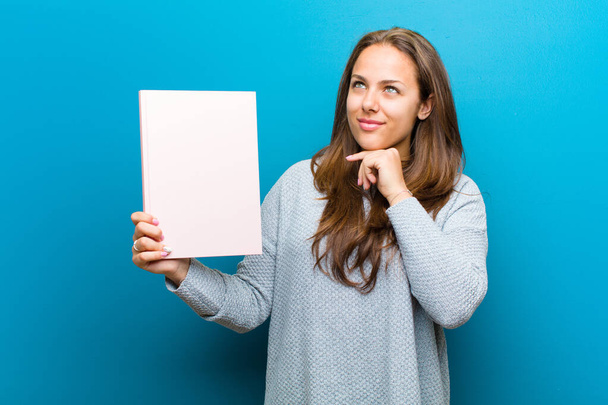 young woman with a notebook against blue background - Fotó, kép