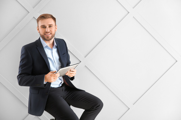 Портрет привлекательного бизнесмена с планшетным компьютером на светлом фоне
 - Фото, изображение