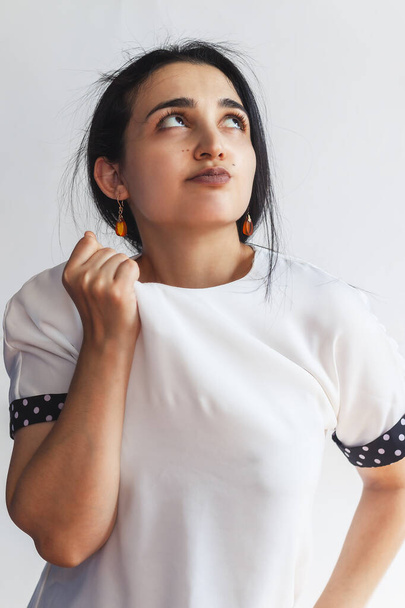 Πορτρέτο μιας γυναίκας με αυτοπεποίθηση, κρατώντας το χέρι κοντά στο πρόσωπο, κοιτάζοντας προς τα πάνω με στοχαστική έκφραση προσώπου. Ελκυστική γυναικεία σκέψη της Μέσης Ανατολής - Φωτογραφία, εικόνα