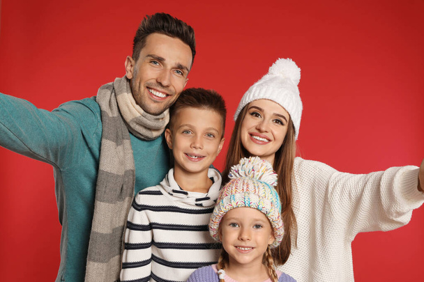 Happy family in warm clothes on red background. Winter season - Zdjęcie, obraz
