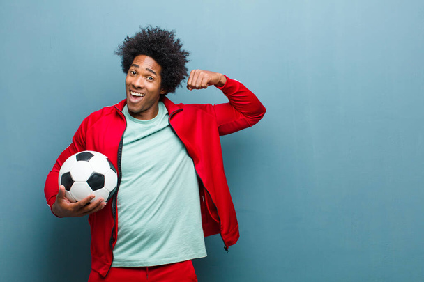 young black sports man with a soccer ball against blue grunge wa - Фото, изображение
