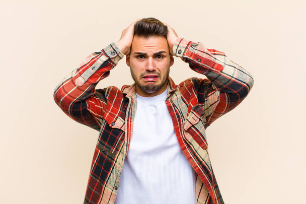 young hispanic man feeling frustrated and annoyed, sick and tired of failure, fed-up with dull, boring tasks against isolated background - Foto, imagen