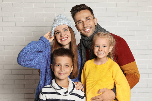 Happy family in warm clothes near white brick wall. Winter season - Foto, imagen