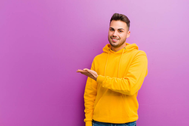 young hispanic man with casual look against purple background - Foto, Imagem