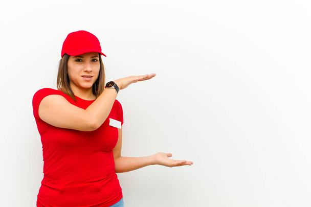 delivery woman holding an object with both hands on side copy space, showing, offering or advertising an object against white background - Фото, изображение