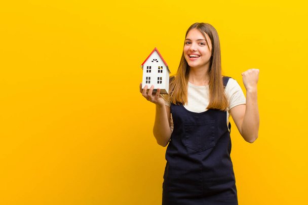 young pretty woman with a house model against orange background - Фото, изображение