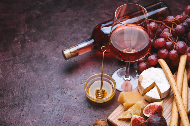 Стекло и бутылка вкусного вина с закусками на цветном фоне
 - Фото, изображение