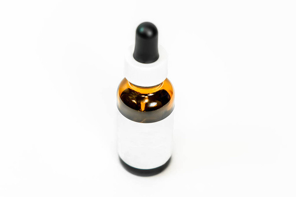 Brown glass eye dropper bottle with lid, and white blank label on a white background, isolated. Room for copy, add your own text. Still life bottle photo. - Photo, Image