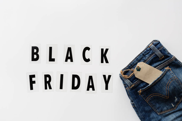 Creative promotion composition Black friday text and jeans on white background. Flat lay, top view, overhead, mockup, template. Minimal abstract background. Online shopping, sale, promo. Web banner - Zdjęcie, obraz